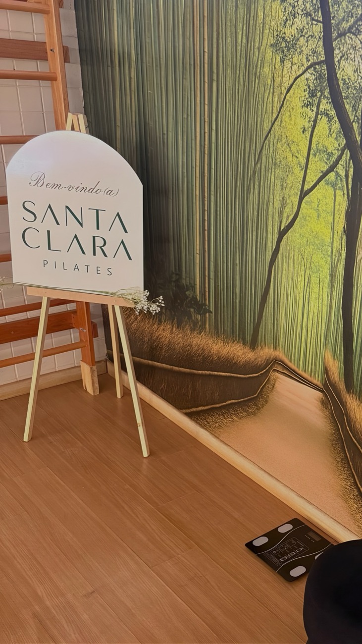 Placa de boas-vindas do Santa Clara Pilates em frente ao painel de bambu